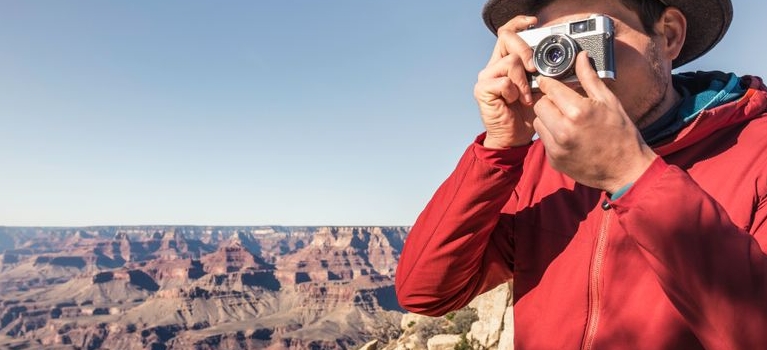 man taking photograph near canyon
